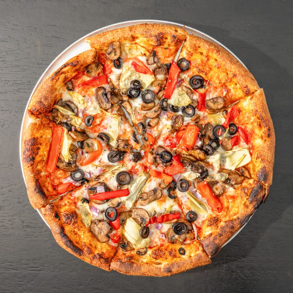 A whole Black Hawk Brewery pizza with mushrooms, olives, red peppers, and artichoke hearts.