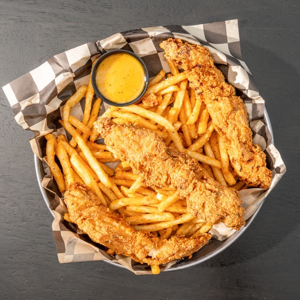 Black Hawk Brewery's crispy chicken tenders and seasoned fries in a metal basket with dipping sauce.