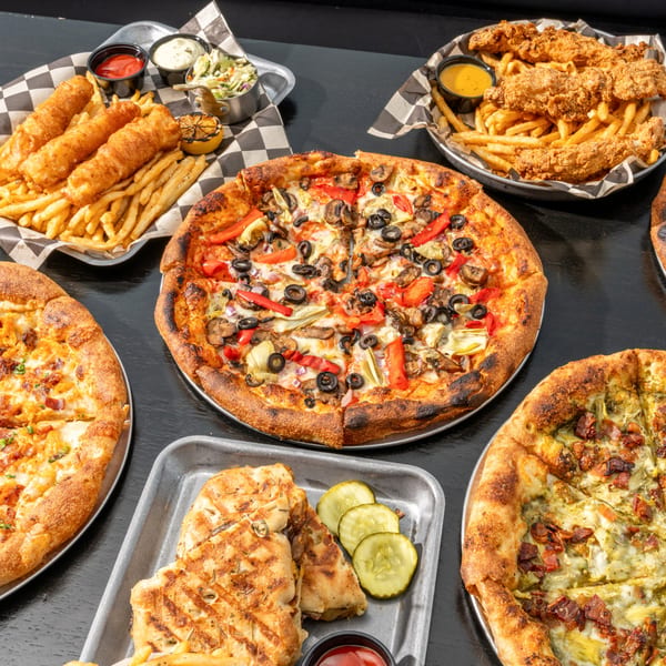 A table laden with Black Hawk Brewery's pizzas, fish and chips, chicken tenders, and grilled sandwiches.