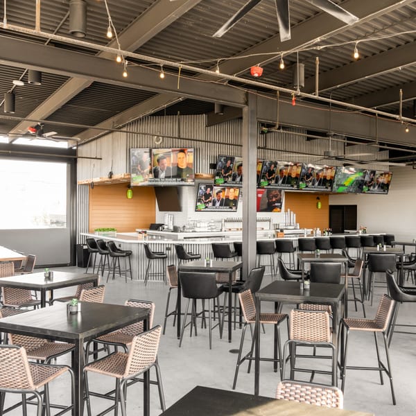 Black Hawk Brewery's sports bar interior with a long bar, high-top tables, and multiple TVs showing sports.