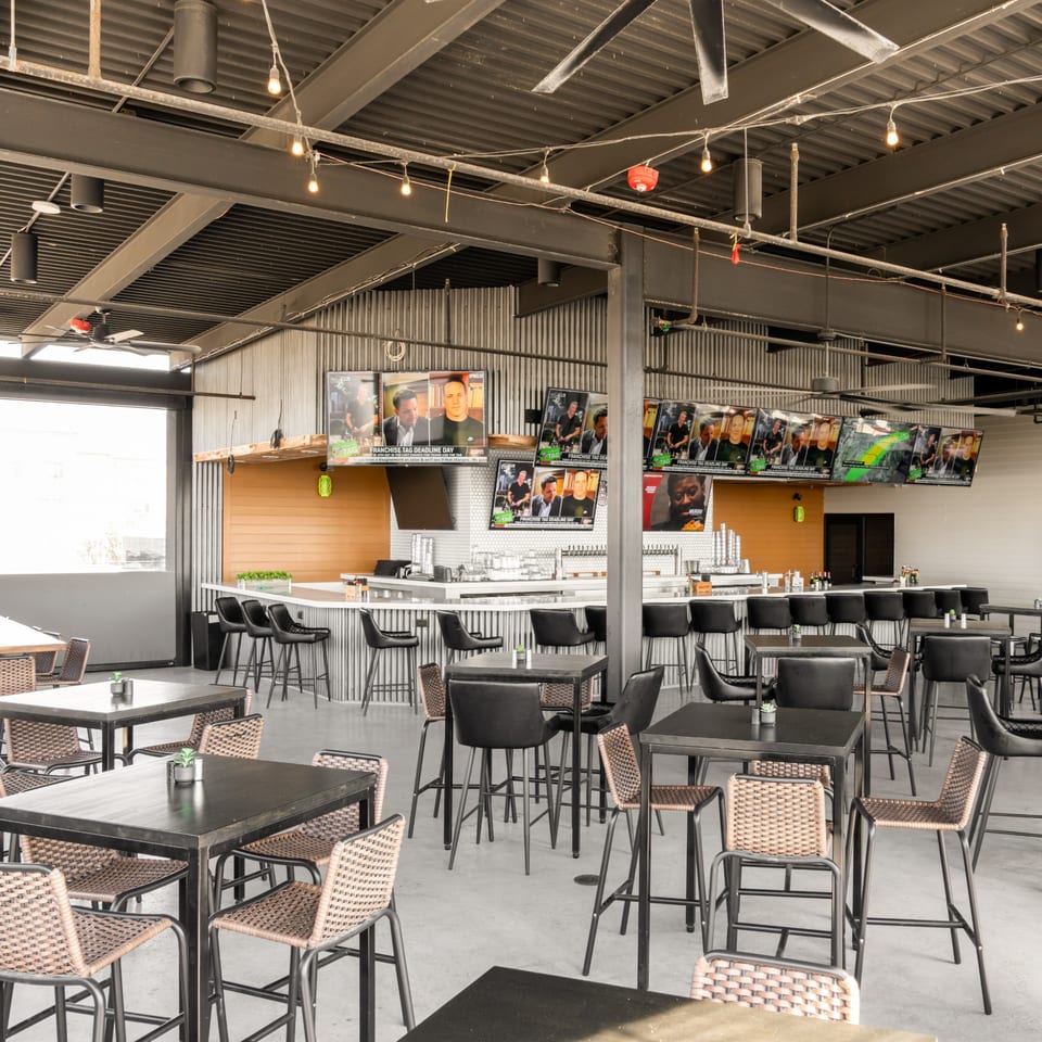 Black Hawk Brewery's sports bar interior with a long bar, high-top tables, and multiple TVs showing sports.