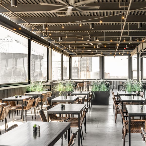 Black Hawk Brewery's spacious sports-bar dining area with tables, chairs, plants, and large windows.