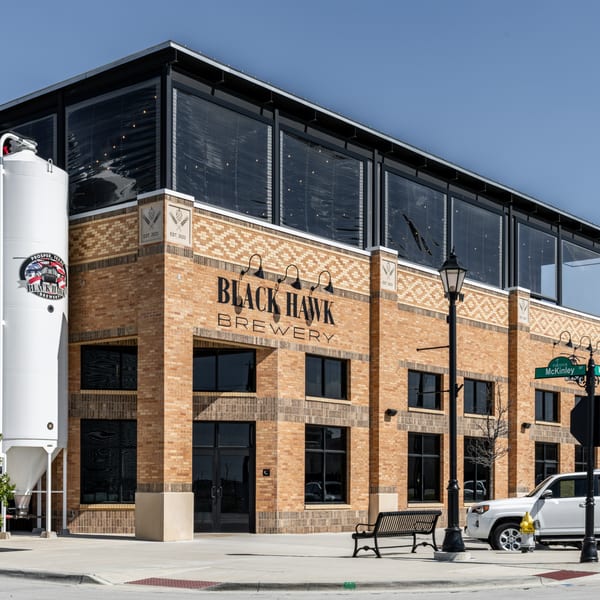 Exterior of Black Hawk Brewery, a brick building with large windows and a white grain silo.